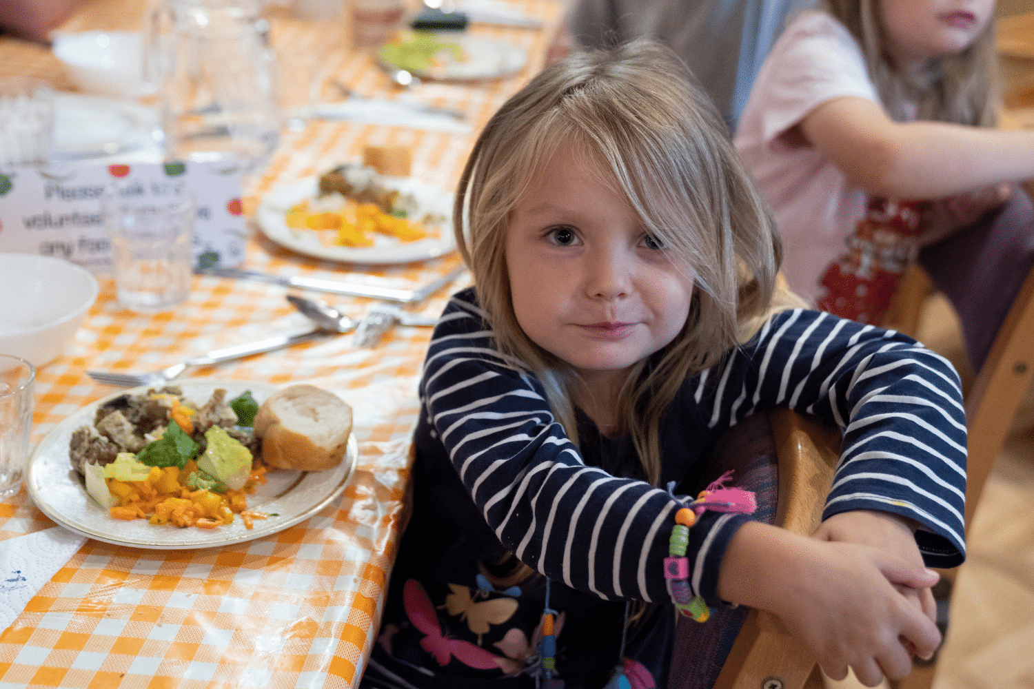 Smiling child eating a healthy vegetarian meal at a school dining table