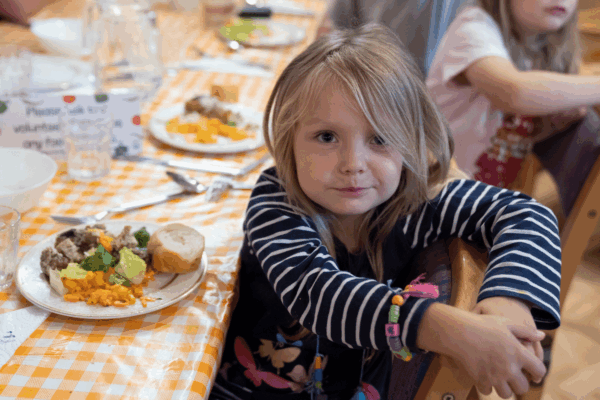 Smiling child eating a healthy vegetarian meal at a school dining table